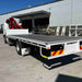 Flatbed truck with crane in front of a warehouse